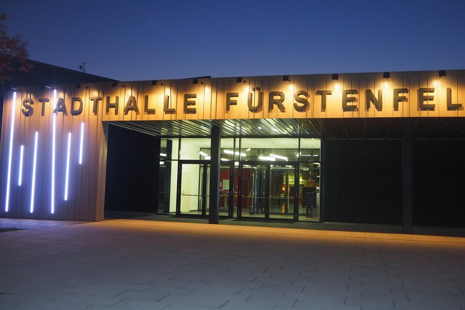 Die Stadthalle Fürstenfeld ist eindrucksvoll beleuchtet und modern gestaltet. Der Eingangsbereich zeigt große, helle Buchstaben. | © Stadtwerke Fürstenfeld
