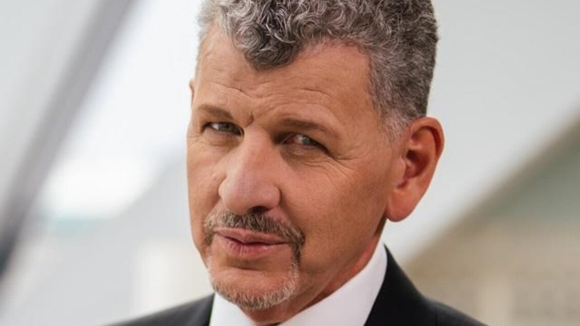 Ein Mann in einem Anzug mit grauem Haar schaut direkt in die Kamera. Der Hintergrund ist unscharf und modern. | © SeminoRossi