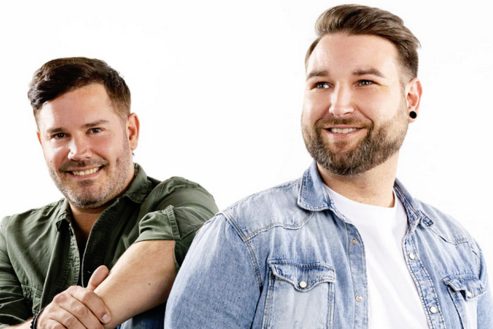 Zwei Männer stehen nebeneinander und lächeln. Sie tragen lässige Kleidung und haben einen freundlichen Ausdruck. | © Bruno Bounty Photography