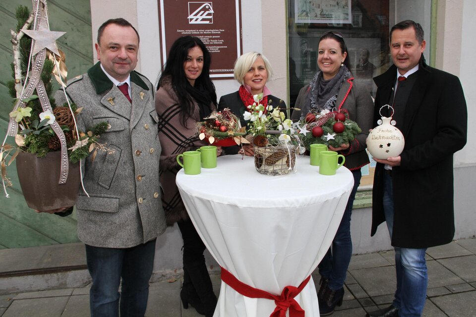 Eine Gruppe von fünf Personen steht um einen Tisch, der mit Dekorationen und Getränken versehen ist. Sie lächeln und scheinen eine festliche Atmosphäre zu genießen. | © Josef Fürbass