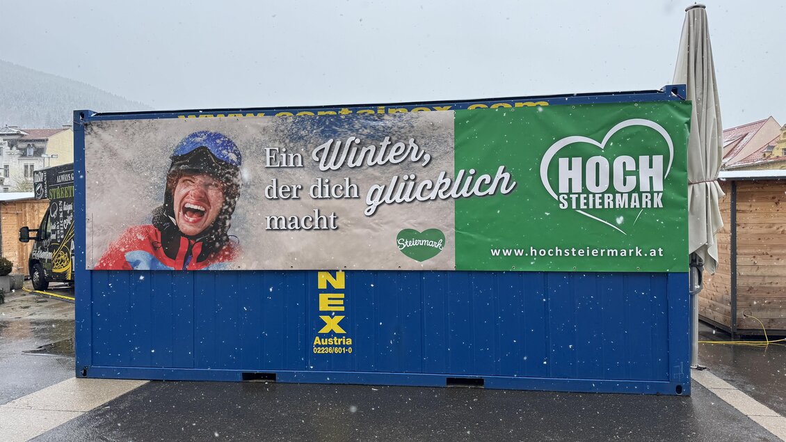 Ein Werbebanner für Hochsteiermark zeigt eine lachende Person im Winter. Der Slogan lautet: „Ein Winter, der dich glücklich macht.“ | © TV Hochsteiermark
