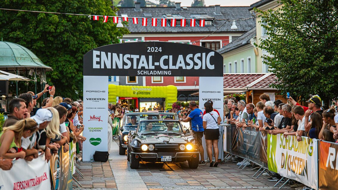 Ein Oldtimer-Rennen findet beim Ennstal-Classic in Schladming statt. Viele Zuschauer stehen am Rand und beobachten die Fahrzeuge. | © Steering Media
