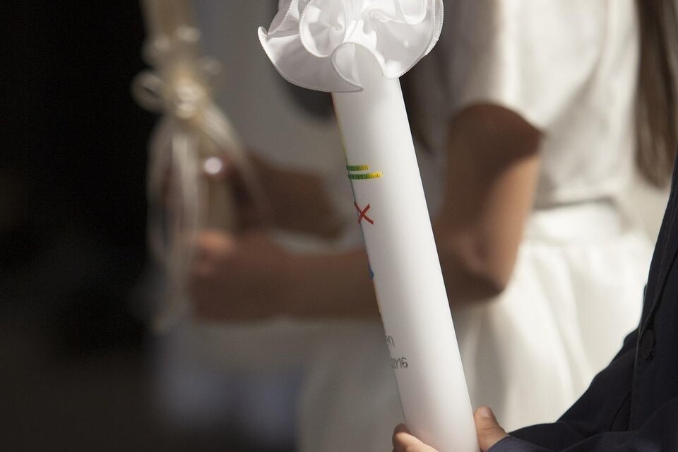 Ein Kind hält eine weiße Kerze mit einer Schleife. Im Hintergrund sind weitere Kinder zu sehen, die ebenfalls Kerzen halten. | © Pixabay