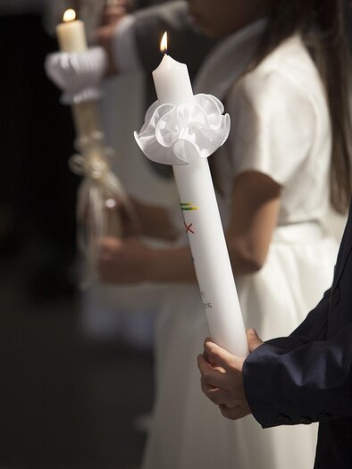 Ein Kind hält eine weiße Kerze mit einer Schleife. Im Hintergrund sind weitere Kinder zu sehen, die ebenfalls Kerzen halten. | © Pixabay