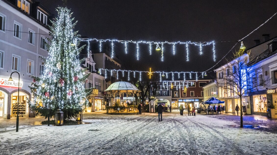 Ein festlich beleuchteter Weihnachtsmarkt bei Nacht. Weihnachtsbaum und schöne Lichter schmücken die verschneite Straße. | © Gerhard Pilz