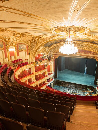An elegant theater with opulent interior and red seating area. The stage is set and awaiting the next performance. | © (c) Graz Tourismus - Harry Schiffer