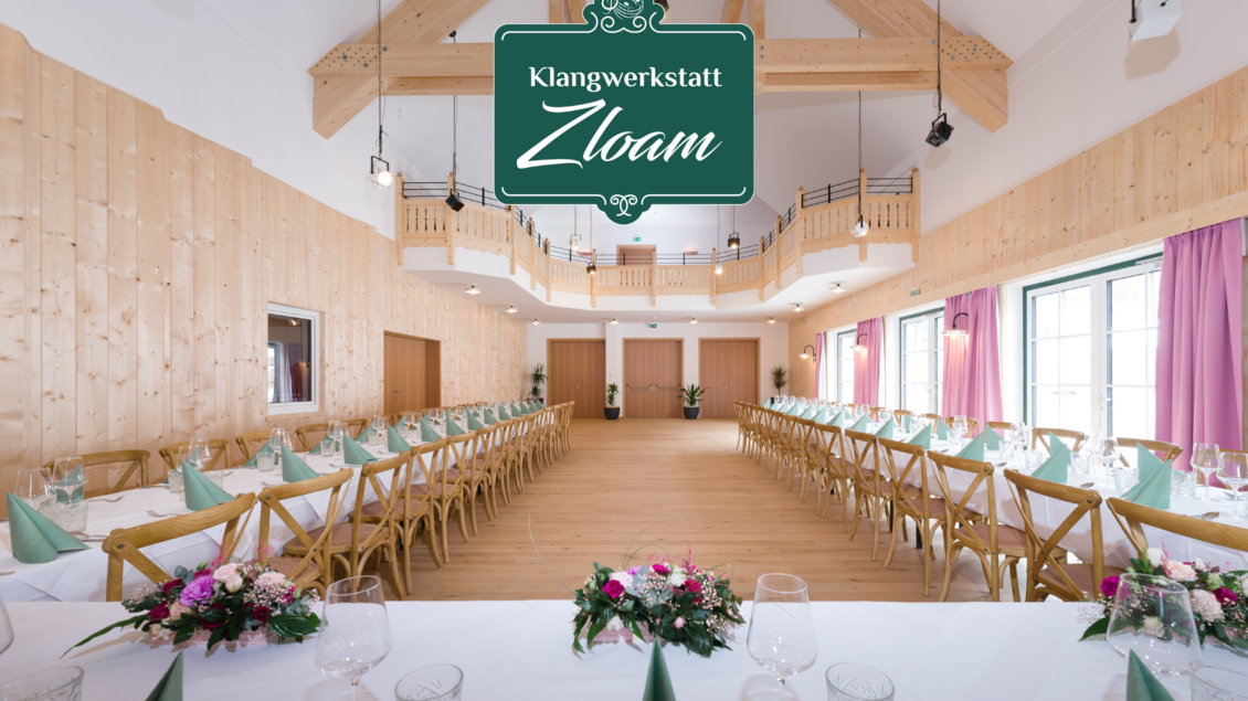 Ein festlich gedeckter Saal mit Holzvertäfelung und langen Tischen. Blumenarrangements und dekorative Elemente sorgen für eine einladende Atmosphäre. | © Narzissendorf Zloam, www.zloam.at