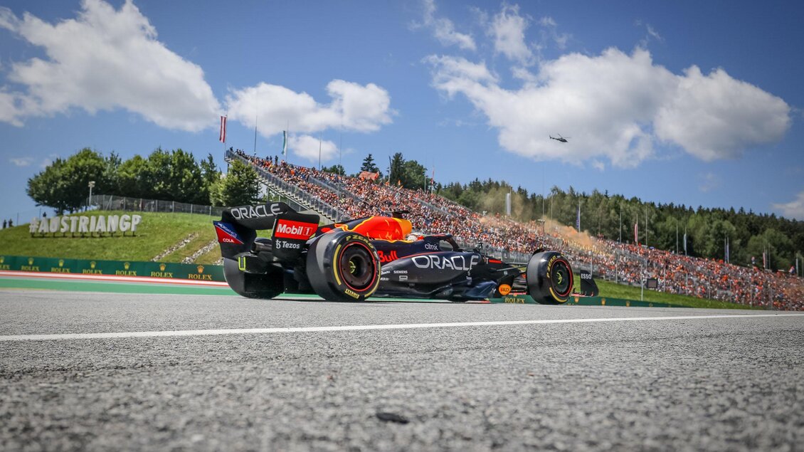 Ein Formel-1-Auto fährt auf der Rennstrecke, umgeben von einer großen Menschenmenge. Der Himmel ist klar und die Landschaft ist grün. | © GEPA Pictures Red Bull Ring