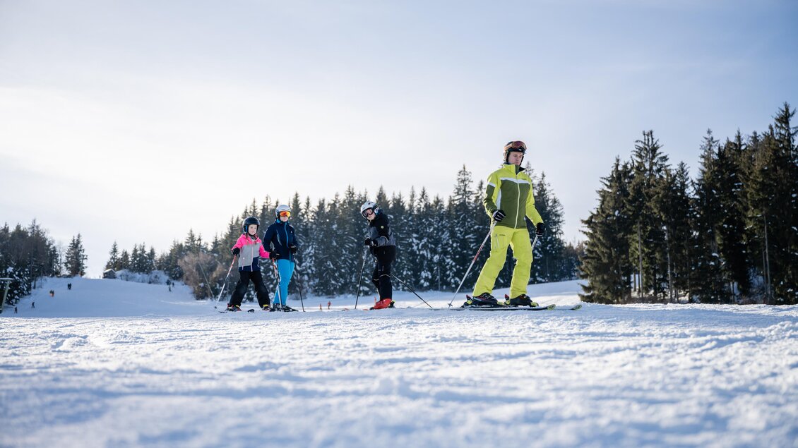 Eine Gruppe von Skifahrern steht auf einer verschneiten Piste. Im Hintergrund sieht man schneebedeckte Bäume und einen klaren Himmel. | © Tourismusverband Oststeiermark