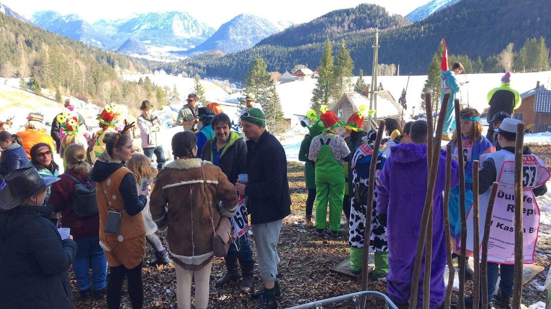 Eine lebhafte Festivität mit Menschen in bunten Kostümen in einer winterlichen Berglandschaft. Im Hintergrund sind schneebedeckte Wiesen und Berge zu sehen. | ©  Christiane Pressl