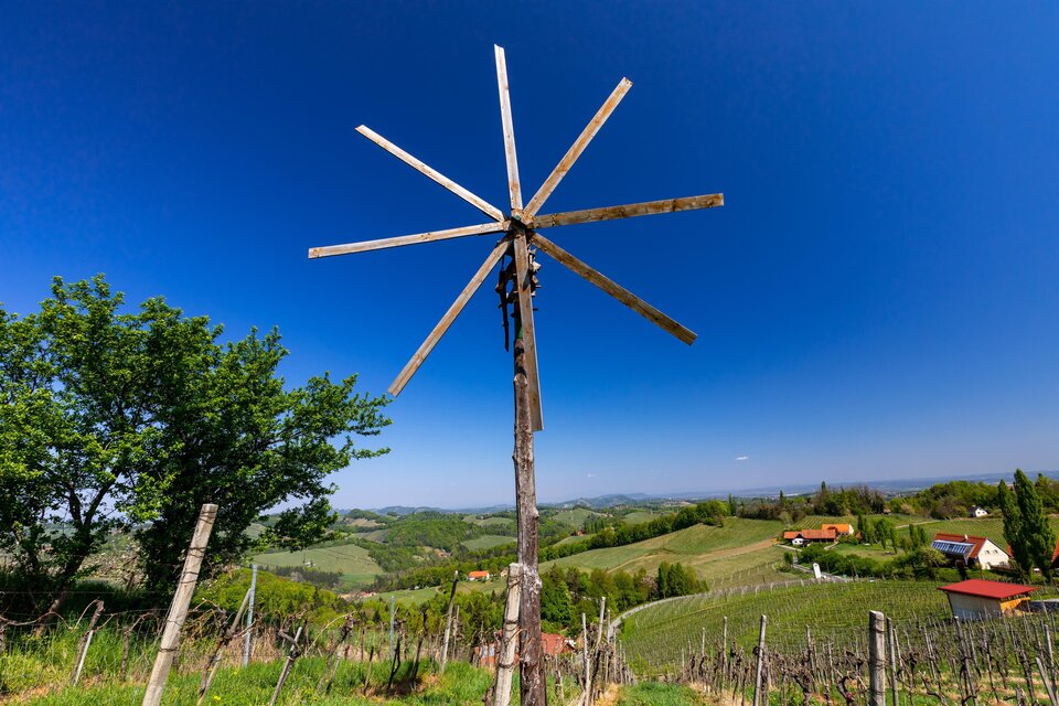 Ein Windrad steht auf einem Hügel mit Blick auf Weinberge. Der Himmel ist klar und blau, die Landschaft ist grün und hügelig. | © TV Südsteiermark Büro Gamlitz