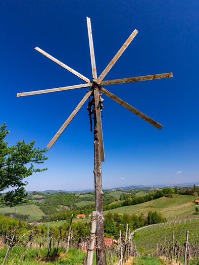 A wind turbine stands on a hill overlooking vineyards. The sky is clear and blue, the landscape is green and hilly. | © TV Südsteiermark Büro Gamlitz