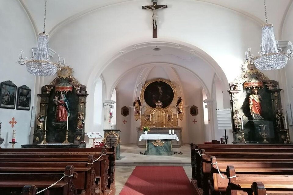 Ein schöner Kirchenraum mit hölzernen Bänken und einer weißen Altaranlage. An den Wänden stehen bunte Skulpturen und Bilder von Heiligen. | © TVB Ausseerland Salzkammergut_Kolb