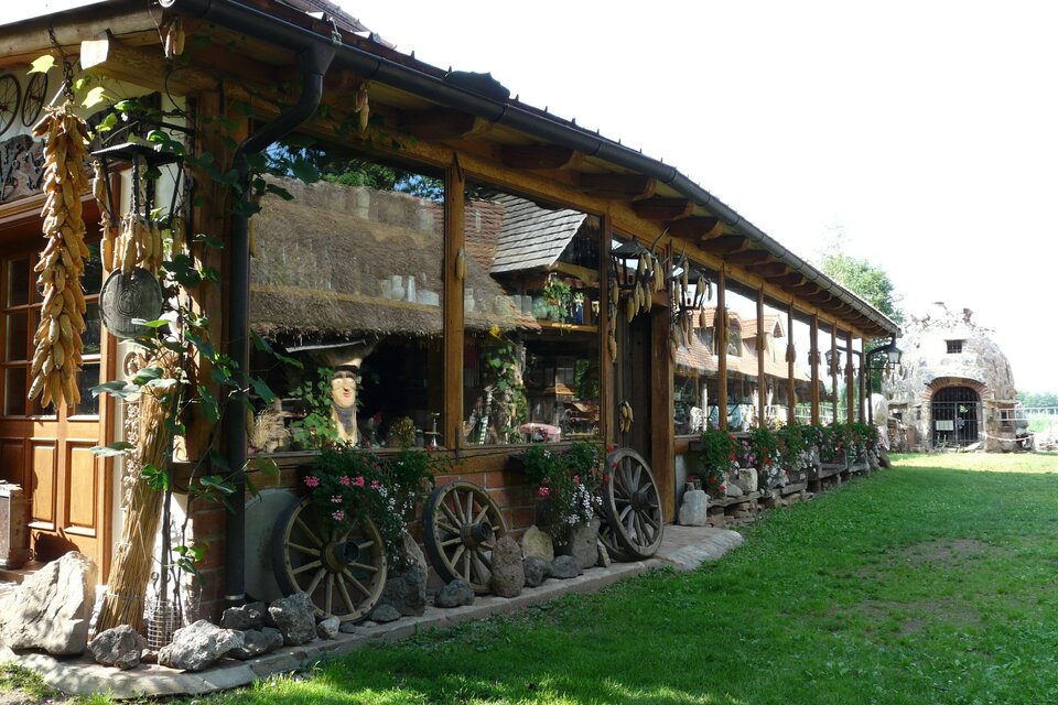 Ein rustikales Gebäude mit Holzverkleidung und einer einladenden Terrasse. Grünflächen und Blumen sorgen für eine schöne Umgebung. | © Bulldogwirt