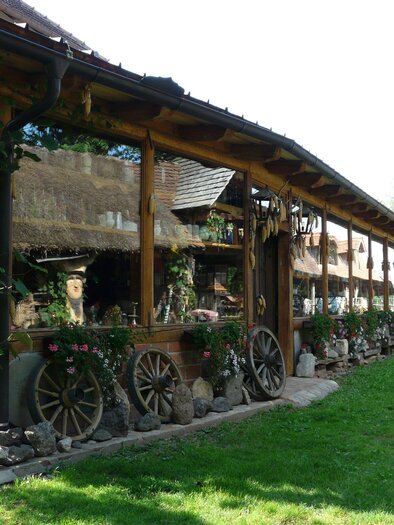 A rustic building with wooden cladding and an inviting terrace. Green spaces and flowers create a beautiful environment. | © Bulldogwirt