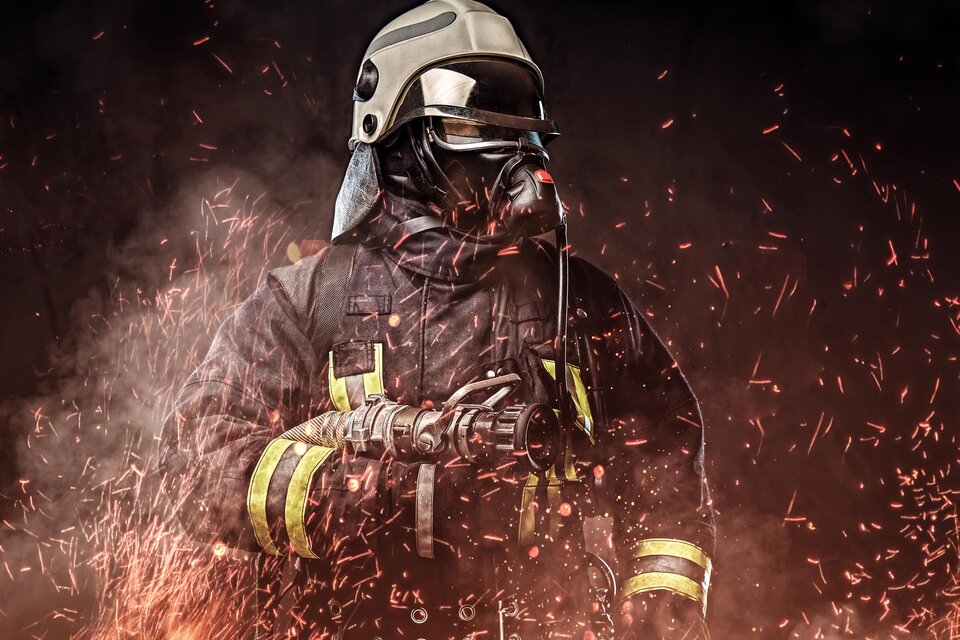 Ein Feuerwehrmann in Schutzkleidung steht vor einem Hintergrund aus Funken und Rauch. Er trägt einen Helm und eine Atemmaske, während er einen Löschschlauch hält. | © px