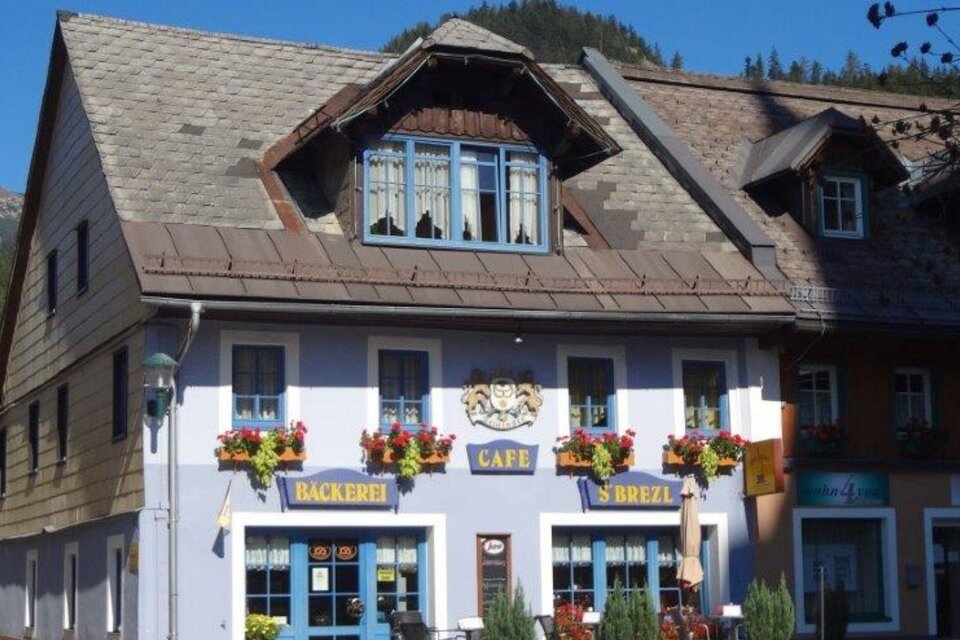 Ein charmantes Gebäude mit einem Café und einer Bäckerei. Vor dem Haus gibt es bunte Blumen und eine gemütliche Atmosphäre.
