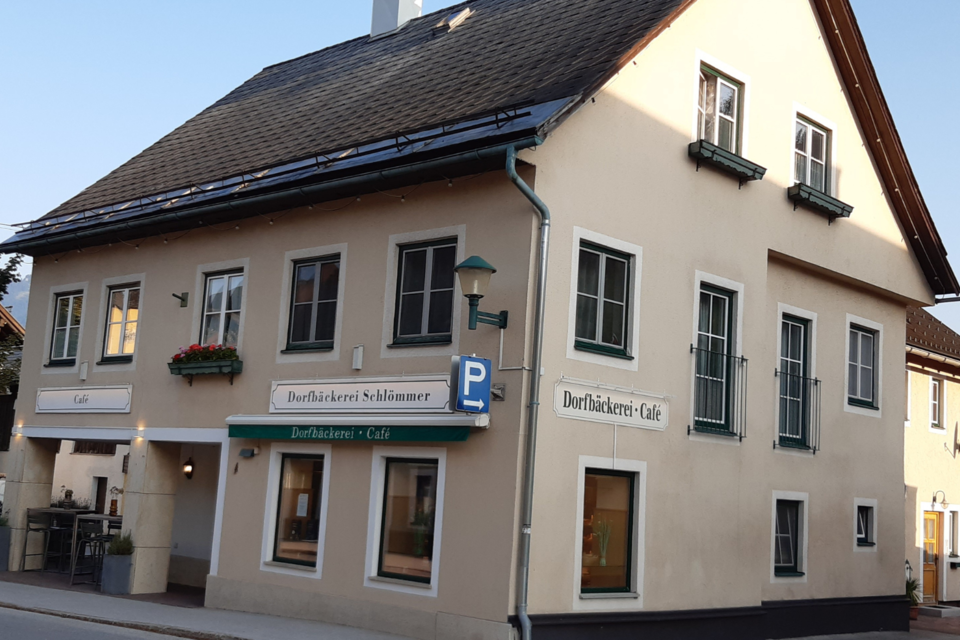 Ein gemütliches Café mit einer hellen Fassade und Fenstern. Vor dem Gebäude befinden sich Blumen und ein Parkplatz. | © TVB Ausseerland Salzkammergut/ Daniela Casari