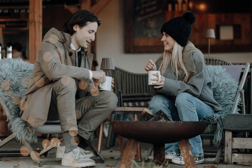Zwei Personen genießen heiße Getränke am Feuer im Adventgarten beim Kreuzwirt in Thal. | © Lukas Brunner