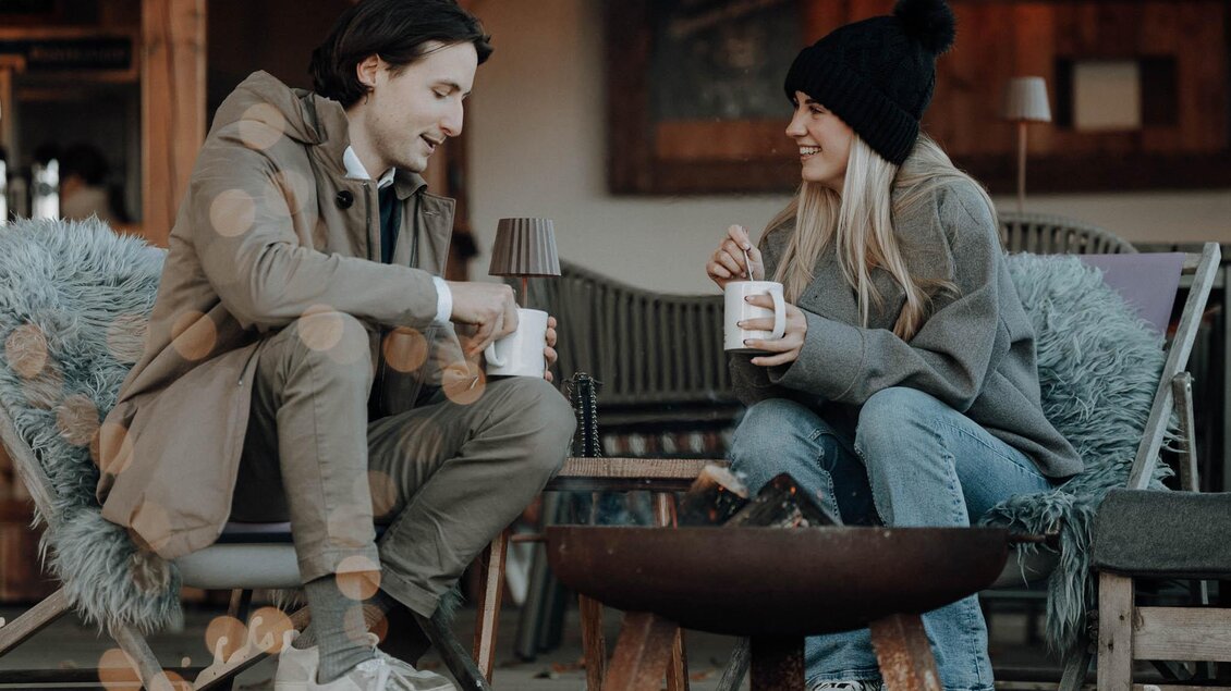 Zwei Personen genießen heiße Getränke am Feuer im Adventgarten beim Kreuzwirt in Thal. | © Lukas Brunner