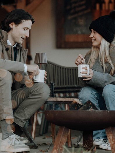 Two people enjoy hot drinks by the fire in the Advent garden at Kreuzwirt in Thal. | © Lukas Brunner