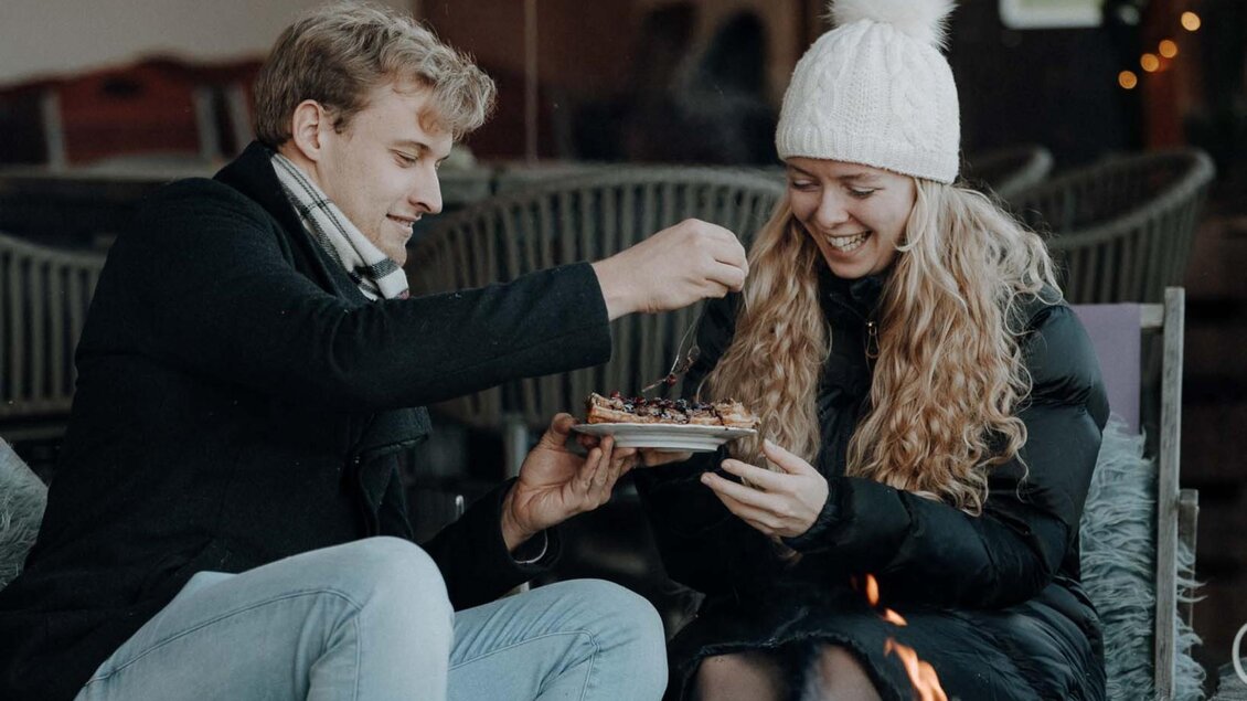 Paar teilt Waffel mit Beeren am Feuer im Adventgarten beim Kreuzwirt in Thal. | © Lukas Brunner