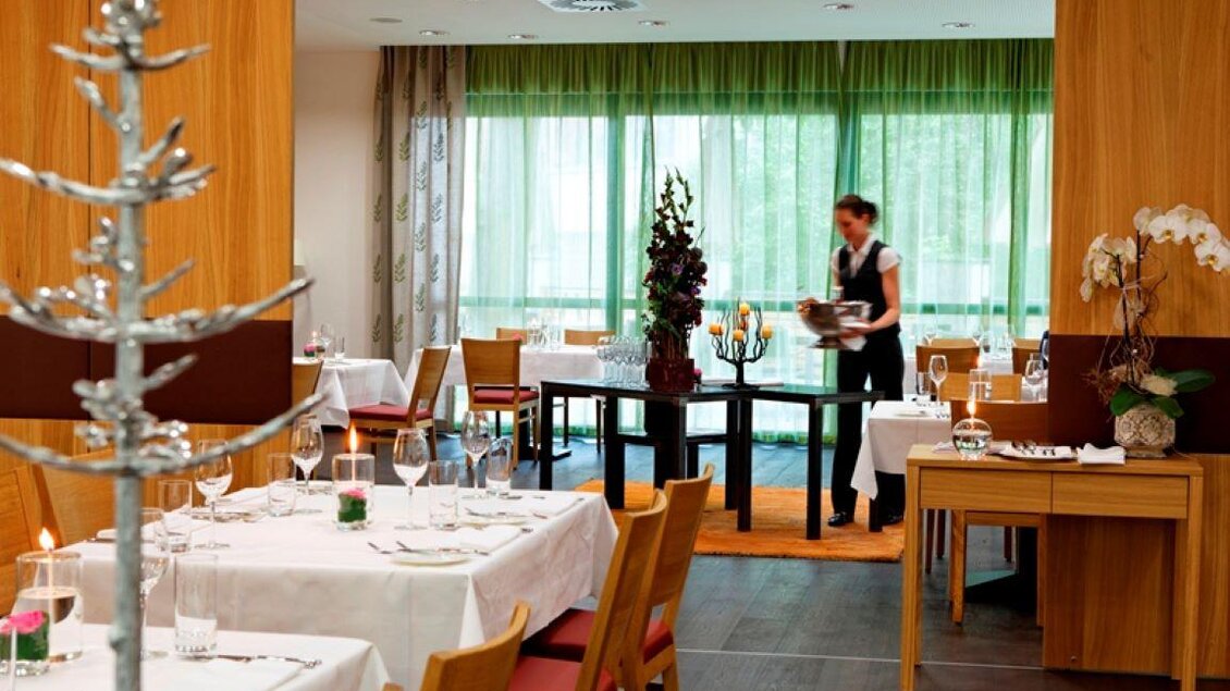 Ein elegantes Restaurant mit gedeckten Tischen und einem modernen Ambiente. Eine Kellnerin serviert Gerichte in einem hellen, einladenden Raum. | © Stainzerhof