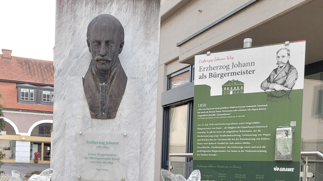 Eine Statue von Erbherzog Johann steht auf einem Podest. Daneben befindet sich ein Informationsschild über seine Rolle als Bürgermeister. | © TV Südsteiermark - Irene Löschnig