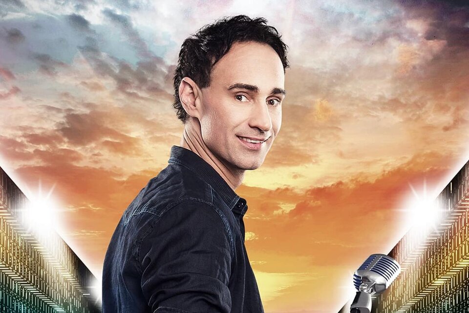 Ein Mann mit einem Mikrofon steht vor einem farbenfrohen Himmel bei Sonnenuntergang. Er blickt lächelnd in die Kamera. | © gernot kulis