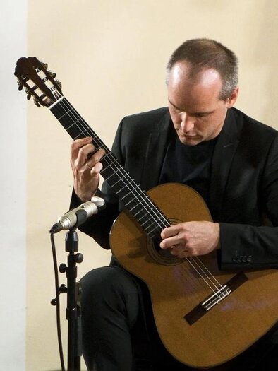 A hand plays a guitar. The fingers move over the strings in a calm moment. | © Walter Schindler