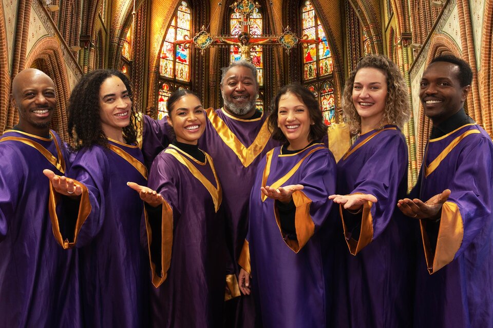 Eine Gruppe von Sängern in lila Gewändern steht in einer Kirche. Sie lächeln und posieren fröhlich vor bunten Fenstern. | © Alina Ivashschenko