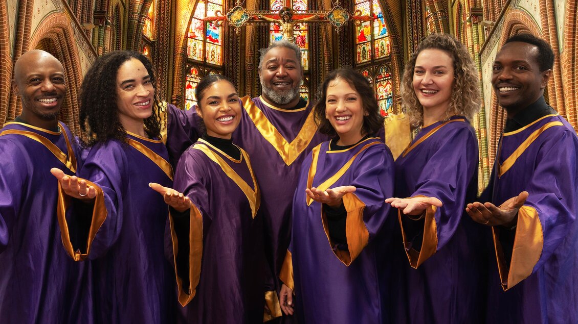 Eine Gruppe von Sängern in lila Gewändern steht in einer Kirche. Sie lächeln und posieren fröhlich vor bunten Fenstern. | © Alina Ivashschenko