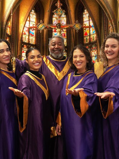 Eine Gruppe von Sängern in lila Gewändern steht in einer Kirche. Sie lächeln und posieren fröhlich vor bunten Fenstern. | © Alina Ivashschenko