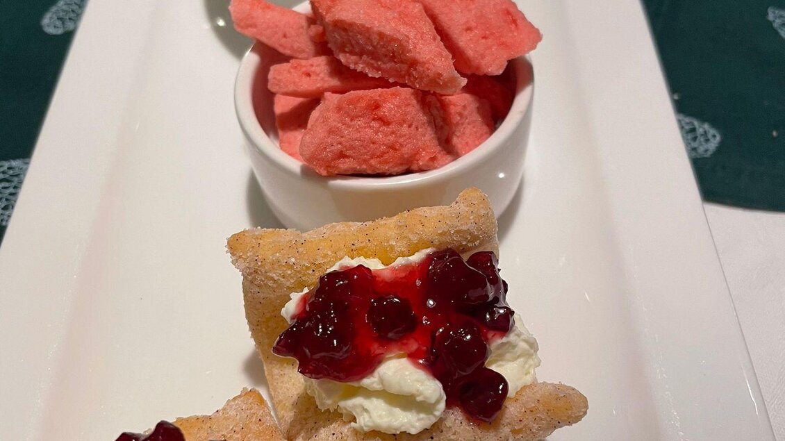 Eine elegante Platte mit kleinen Gebäckstücken, gefüllt mit Sahne und Marmelade. Dazu zwei Schälchen mit farbigen Süßigkeiten. | © Andreas Wieser