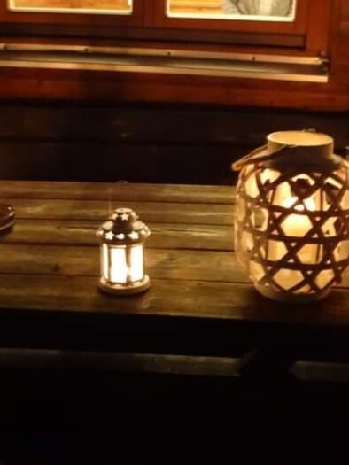 A rustic wooden surface with several lanterns that glow in the dark. In the background, a window is visible, radiating warm light. | © ©Thermen-&Vulkanland/Christian Rossmann