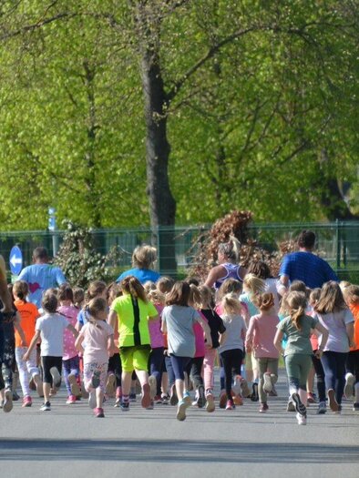 Eine Gruppe von Kindern läuft enthusiastisch auf einem Weg. Im Hintergrund fährt ein Mann auf einem Fahrrad. | © Tourismusverband Oststeiermark