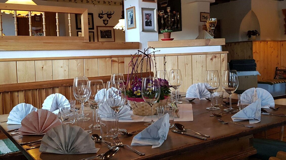 Ein elegant gedeckter Tisch mit schön gefalteten Servietten und Gläsern. Im Hintergrund sieht man eine rustikale Holzwand und dekorative Elemente. | © Stephanie Bor