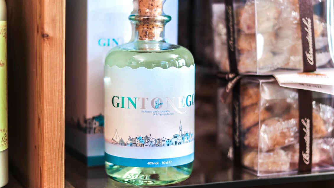 Eine dekorative Flasche Gin steht auf einem Regal. Im Hintergrund sind weitere Produkte in Verpackungen zu sehen. | © Altstadthaus