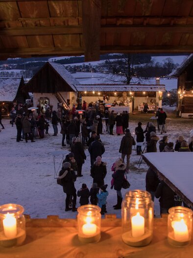 A festive Christmas market at night, illuminated by candles and lights. People stroll between the stalls and enjoy the cozy atmosphere. | © Klaudia Riebenbauer