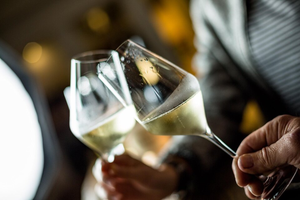 Zwei Gläser Sekt stoßen an. Im Hintergrund sind unscharfe Lichter zu sehen. | © TV Südsteiermark