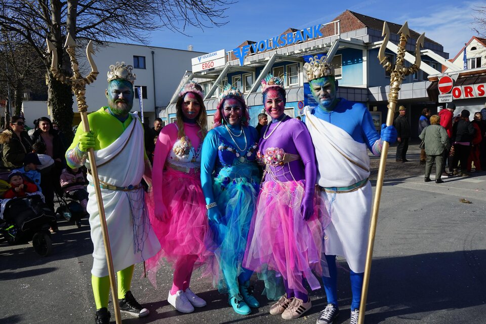 Fünf Personen in bunten Kostümen stehen auf einer Straße. Sie sind mit glitzernden Accessoires und farbiger Schminke geschmückt. | © Stadtgemeinde Köflach
