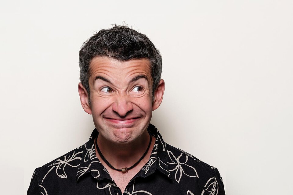 Ein Mann mit einem humorvollen Gesichtsausdruck trägt ein schwarzes Hawaii-Hemd. Der Hintergrund ist schlicht und hell. | © Stefan Gergely