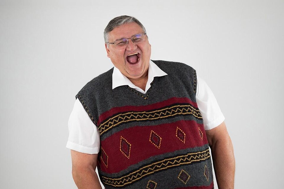 Ein lachender Mann trägt einen grauen Pullover mit buntem Muster. Der Hintergrund ist hell und neutral. | © attack