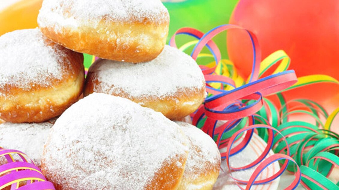 Eine Auswahl von zuckersüßen Berliner, die auf einem bunten Tisch liegen. Umgeben von Festdekoration und Luftballons. | © Fotolia