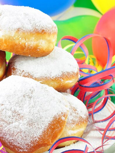 Eine Auswahl von zuckersüßen Berliner, die auf einem bunten Tisch liegen. Umgeben von Festdekoration und Luftballons. | © Fotolia