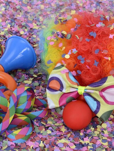 Colorful carnival still life with confetti, streamers, a clown wig, a colorful bow tie, red nose, and a toy trumpet. | © Pixabay