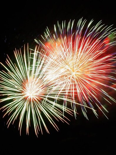 Colorful fireworks light up against a dark background. The explosions radiate in the colors red, green, and white. | © Pixabay