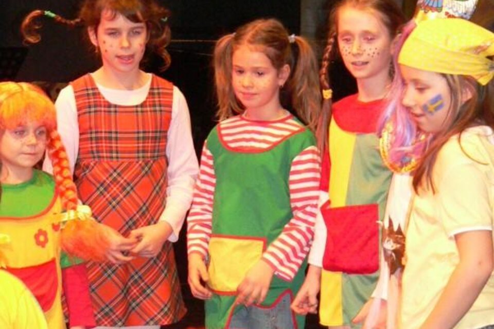 Sechs Mädchen in bunten Kostümen stehen auf der Bühne. Sie haben fröhliche Gesichter und sind geschminkt. | © Lederer