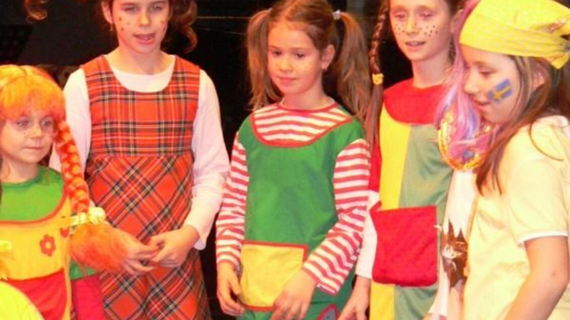 Sechs Mädchen in bunten Kostümen stehen auf der Bühne. Sie haben fröhliche Gesichter und sind geschminkt. | © Lederer