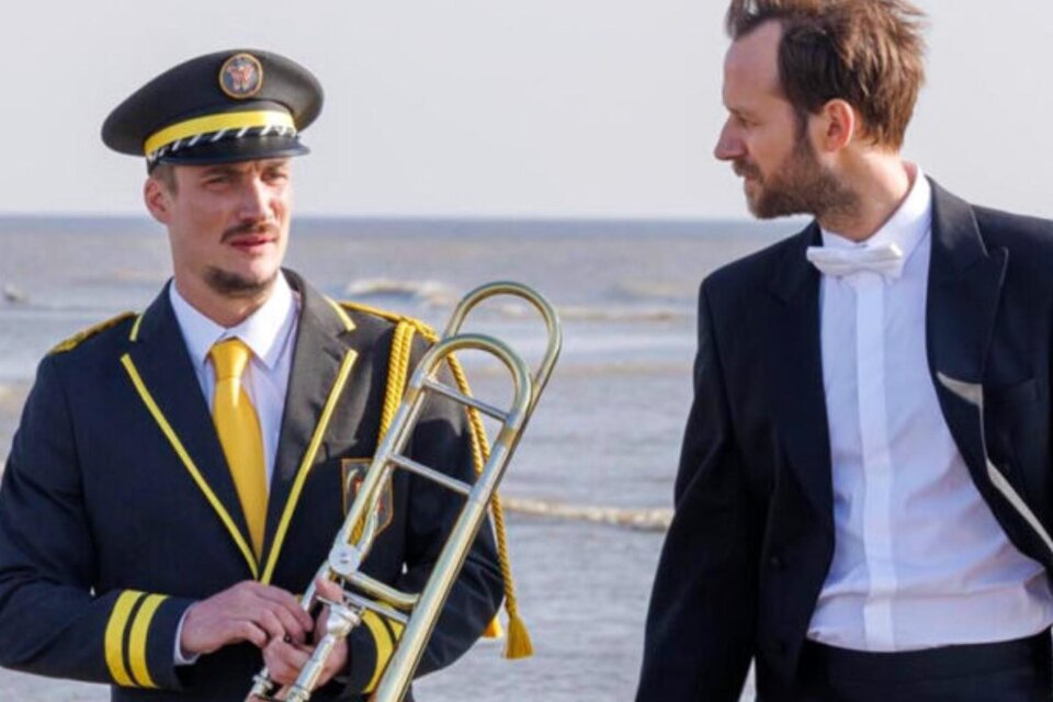 Zwei Männer in Uniform und Frack mit Posaune am Meer, Szene aus Musikfilm. | © Thibault Grabherr